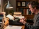 T. Allen Greenfield writing at his desk with UFOnauts book highlighted, promoting https://tallengreenfield.com for literary insights.
